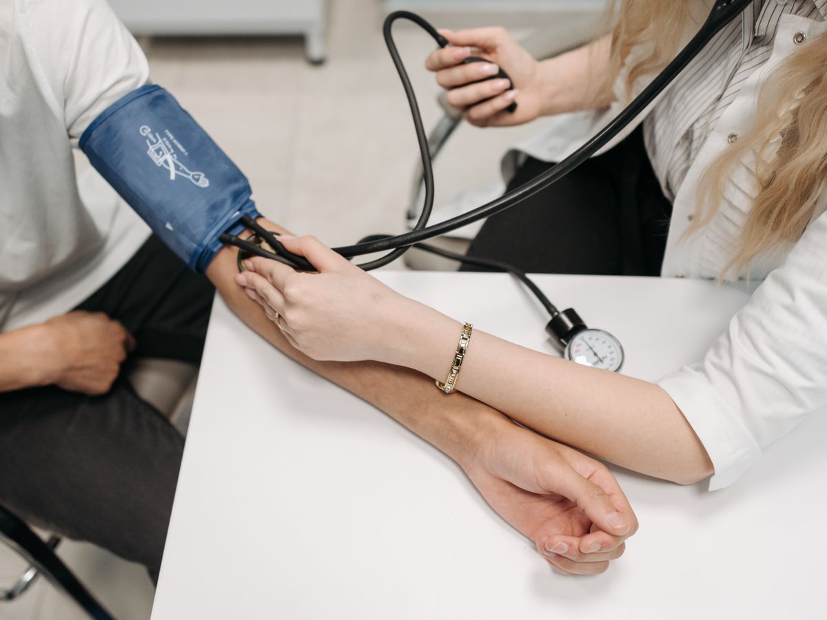 A clinician checks a patient's blood pressure with a cuff at a clinic