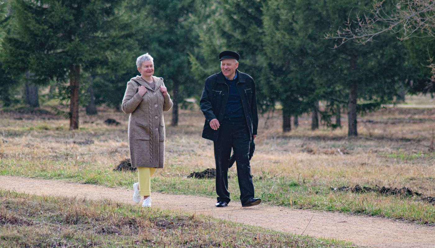 An older couple walks together along a park path